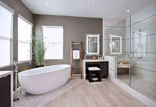 Modern bathroom with freestanding bathtub, glass-enclosed shower, wooden flooring, vanity with mirror, and indoor plant by the window.