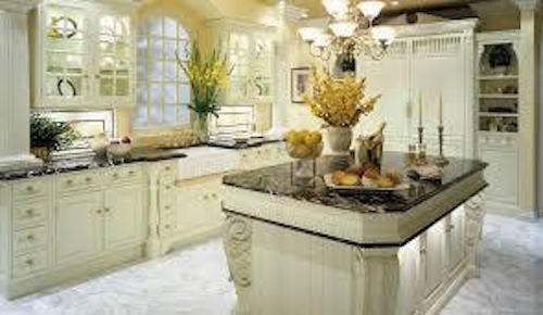 Elegant kitchen renovation with cream-colored cabinetry, dark granite countertops, glass display cabinets, and a central island with decorative details.
